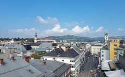 Vor uns die Linzer Landstraße und im Hintergrund das Wahrzeichen von Linz, der Pöstlingberg.